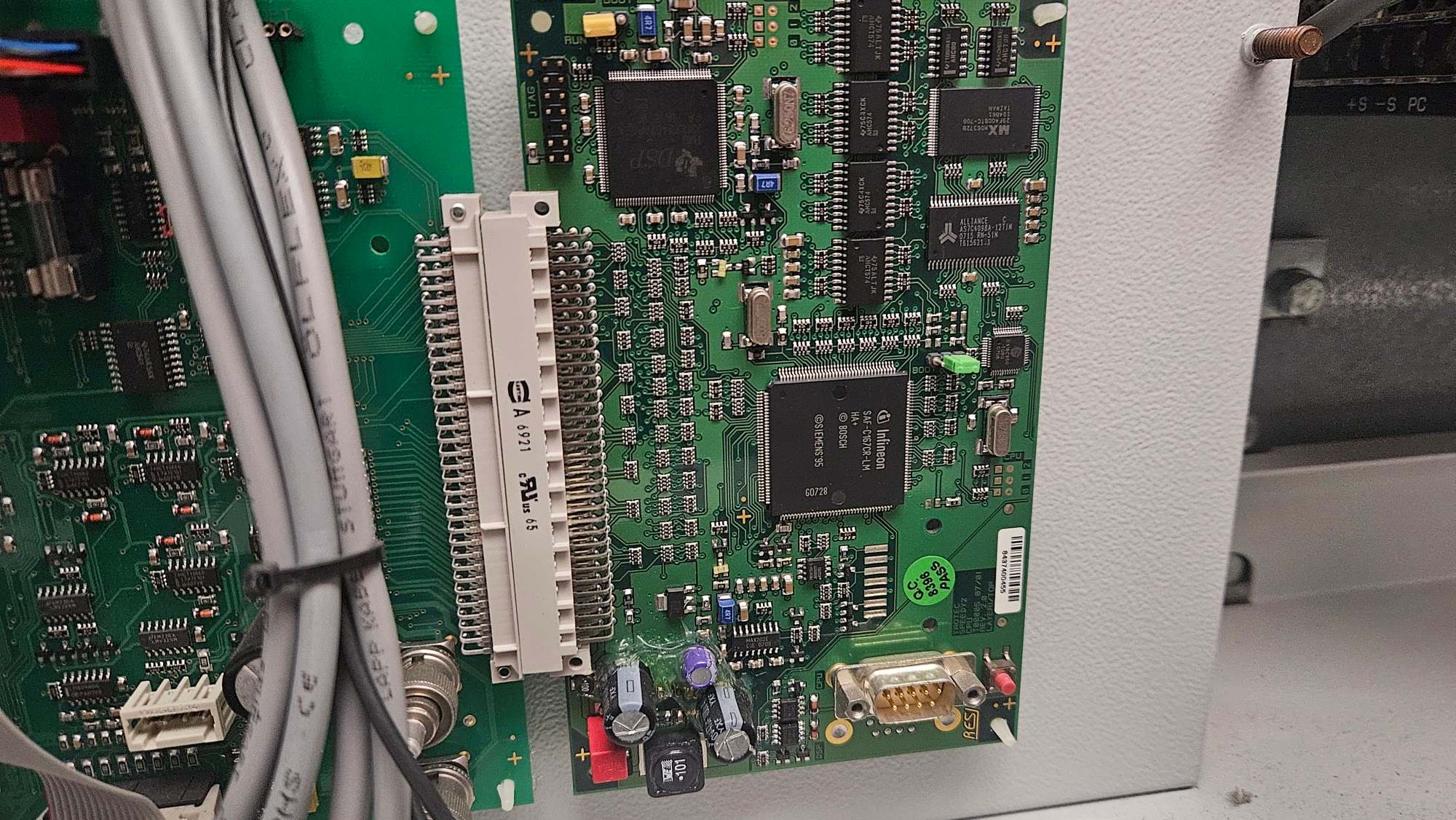 Green controller circuit board with a large processor chip, a 64-pin connector and a DB9 serial connector